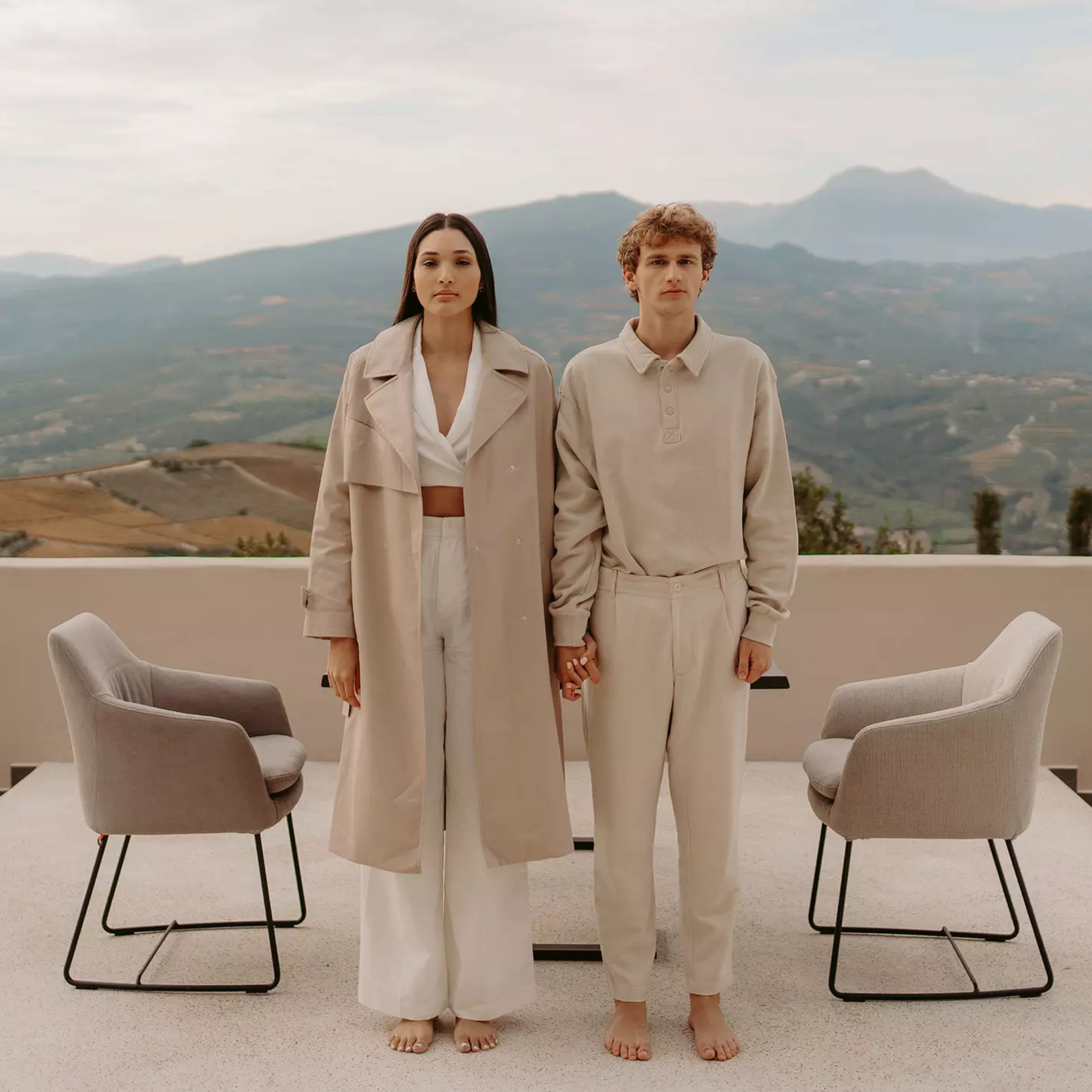 Paar in beiger Kleidung mit Mobitec-Lounge-Stühlen auf minimalistischer Terrasse mit Panoramablick – Outdoor-Lifestyle trifft Designkomfort.