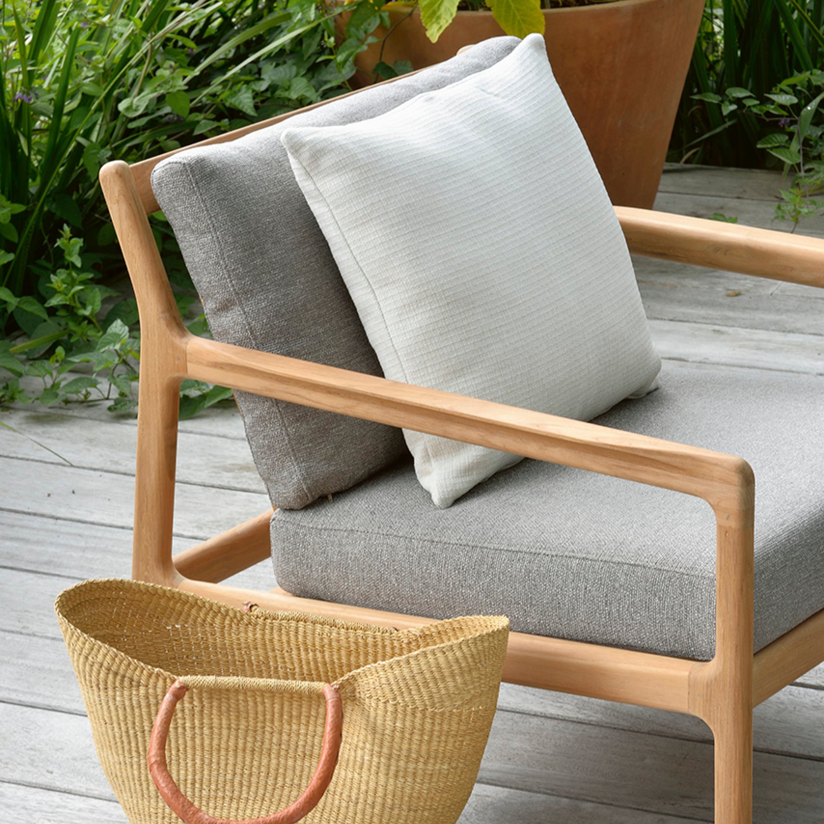 Gartensessel aus hellem Holz mit grauen Polstern – bequemer Outdoorstuhl auf Terrasse mit Naturkulisse
