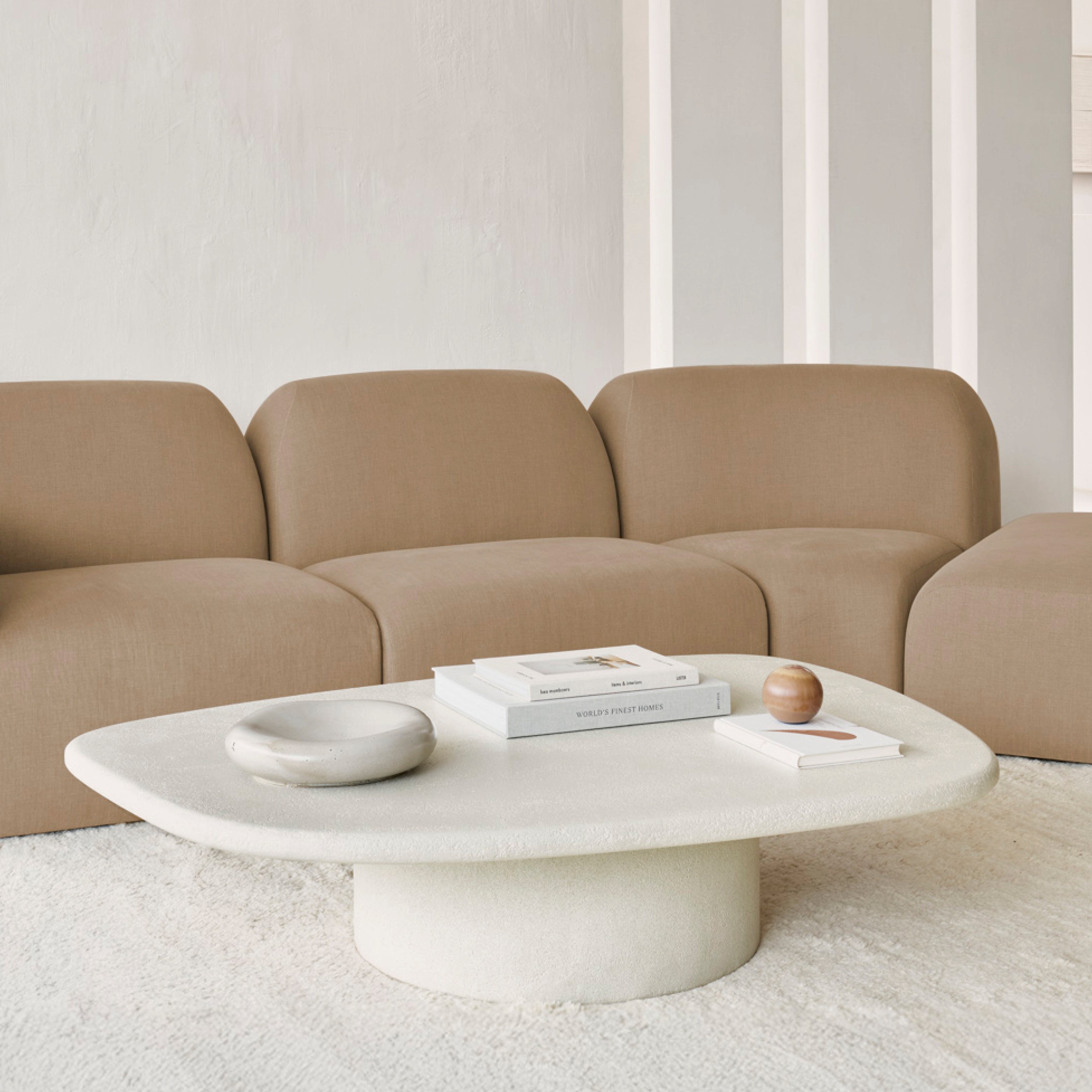 eistelltischs in Mikrozement von der Kollektion Elements – minimalistisch platziert neben Sofa und Accessoires im modernen Wohnraum.