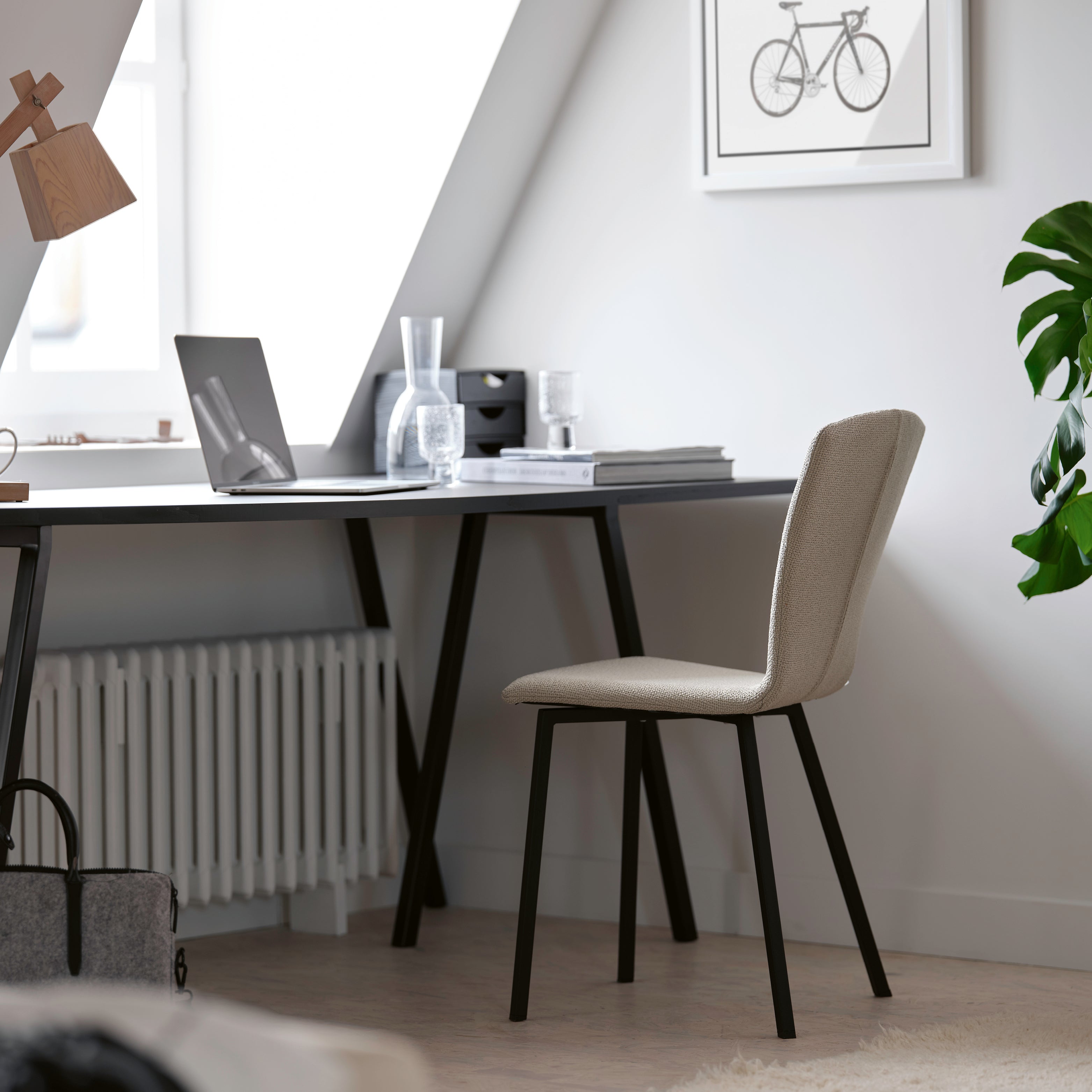 Moderner Bürostuhl mit gepolsterter Sitzfläche und Metallgestell – stilvolles Homeoffice unter dem Dachfenster mit Laptop und Schreibtisch