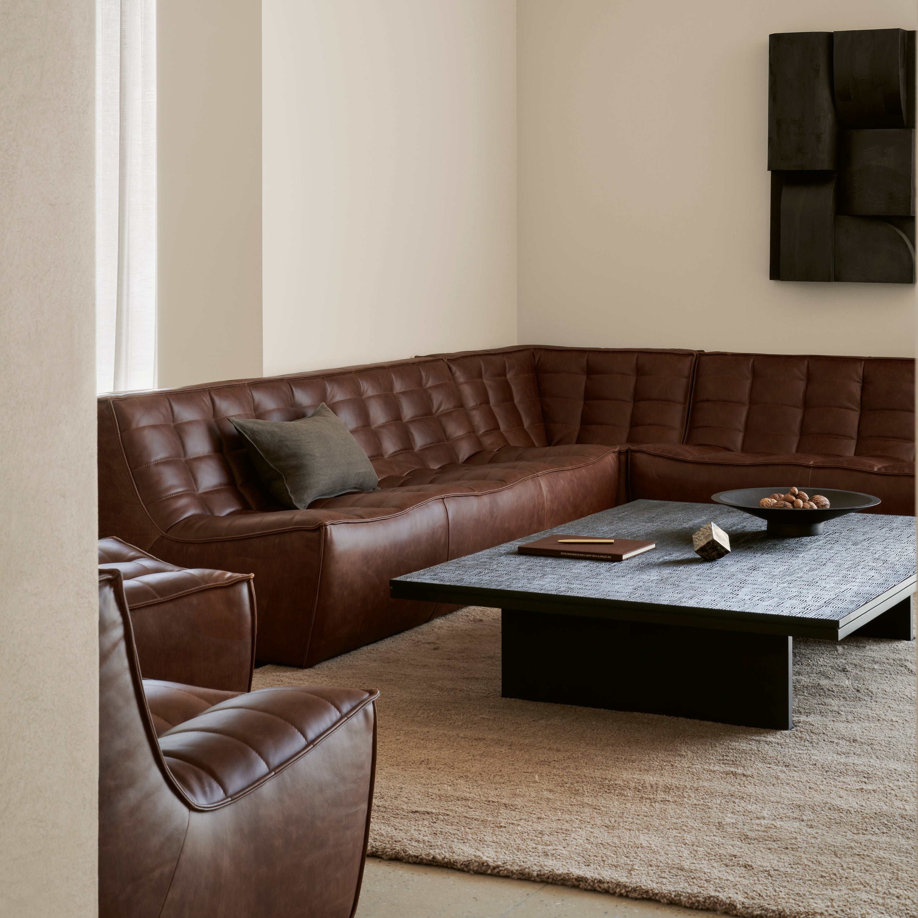 Ethnicraft Ledersofa in L-Form mit Strukturkissen – gemütlicher Wohnbereich mit belgischem Design.