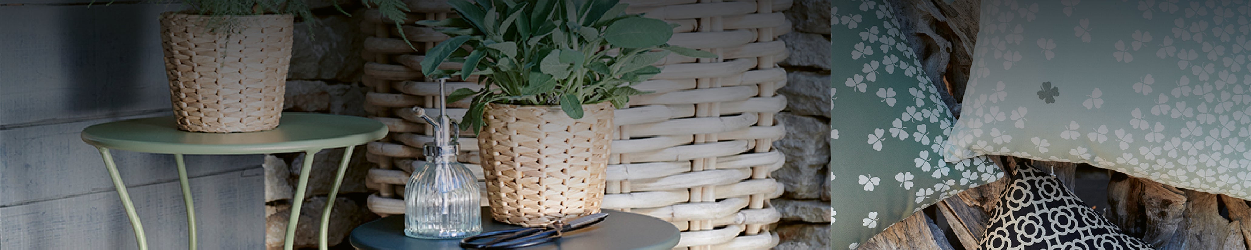 Geflochtene Pflanztöpfe mit Kräutern auf farbigen Outdoor-Tischen neben stilvollen Gartenkissen