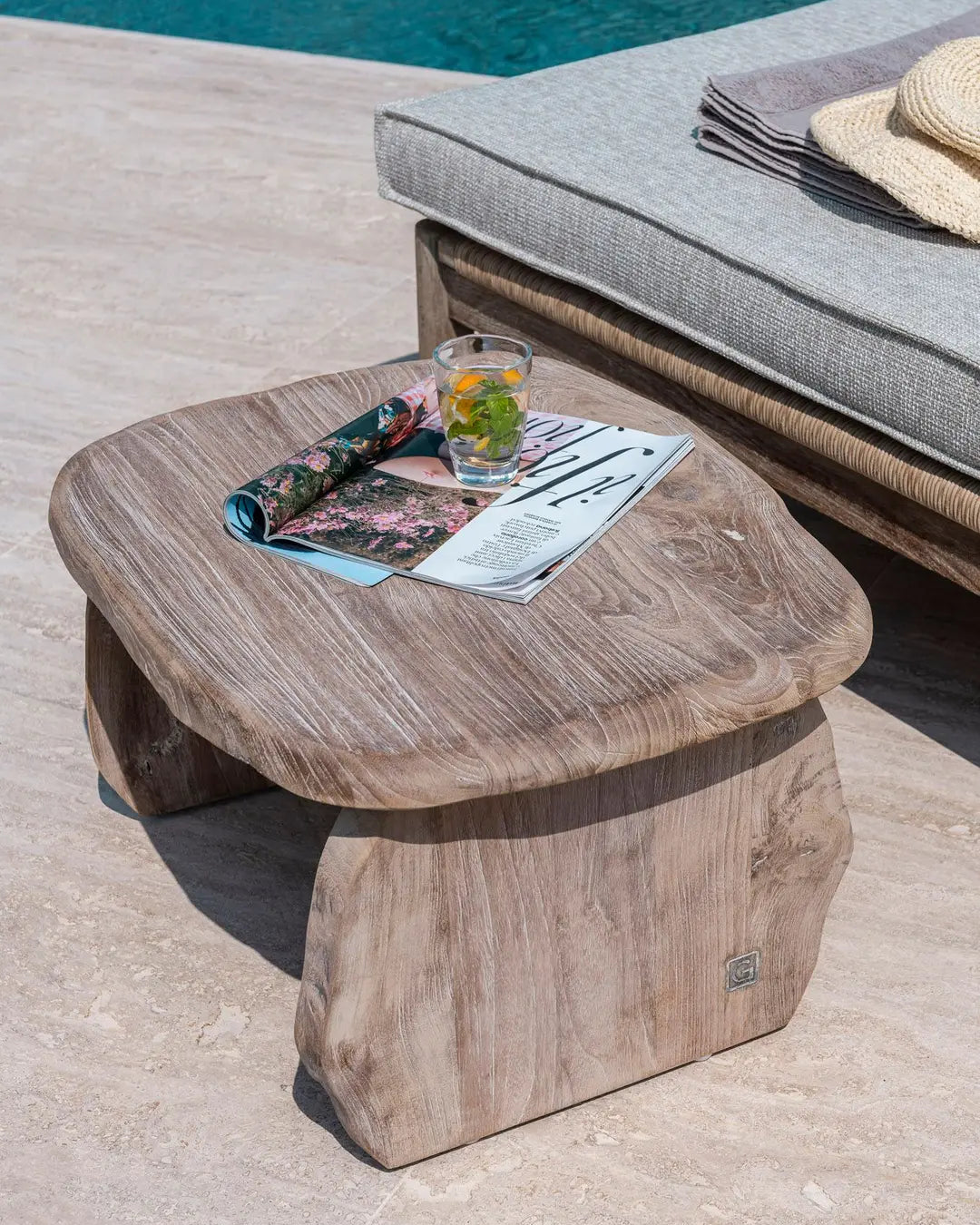 Einrichtungsbild mit Beistelltisch PEBBLE von Gommaire – natürlicher Teaktisch in organischer Form, kombiniert mit Lounge-Möbeln auf einer stilvollen Terrasse