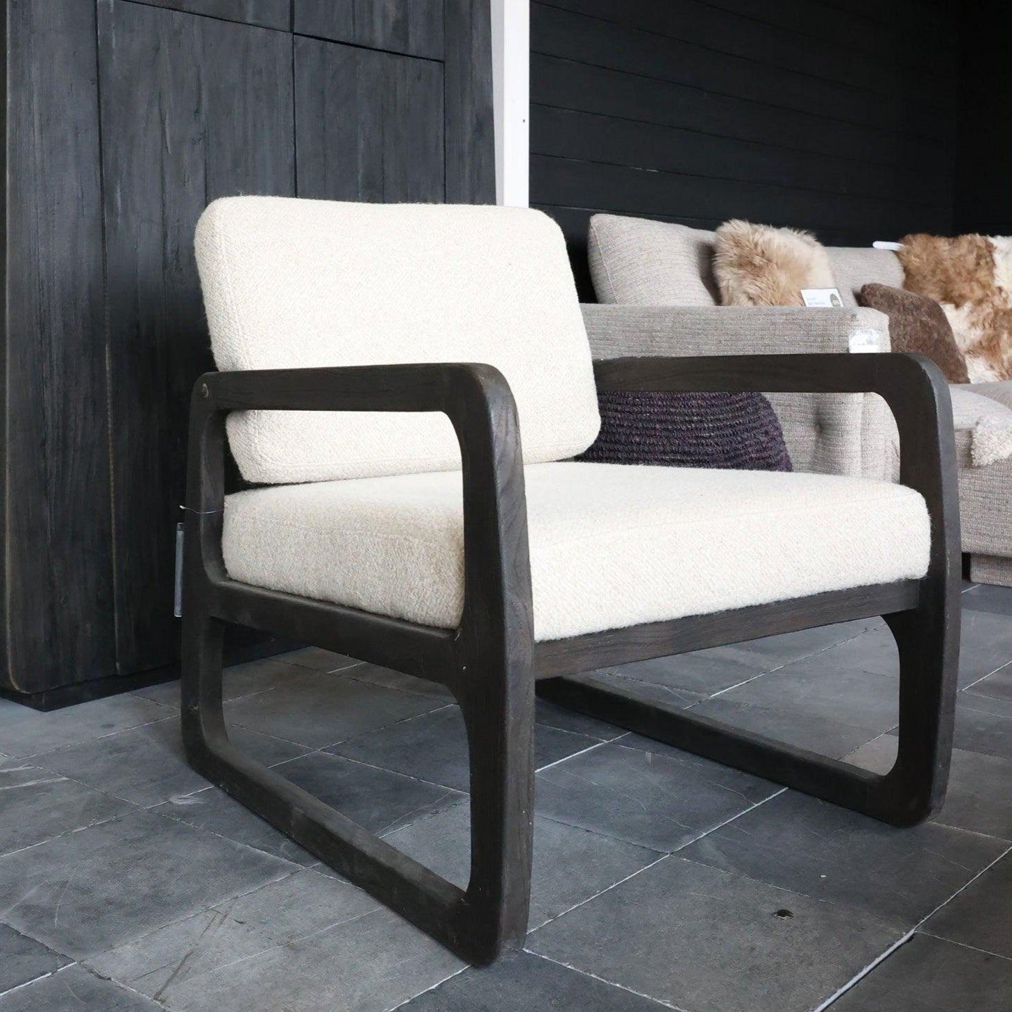 Sessel SALLY UPHOLSTERED von Gommaire – frontal aufgenommen auf einer Design-Expo, präsentiert mit Stoffbezug und Massivholzgestell in modernem Ausstellungsambiente