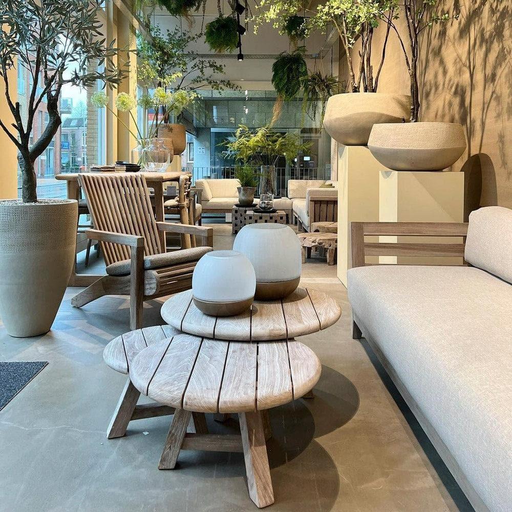 Couchtisch ANTON Set von Gommaire vor Gartensofa – natürliche Kombination aus drei runden Teak-Tischen in abgestufter Höhe, perfekt für moderne Gartenlounges