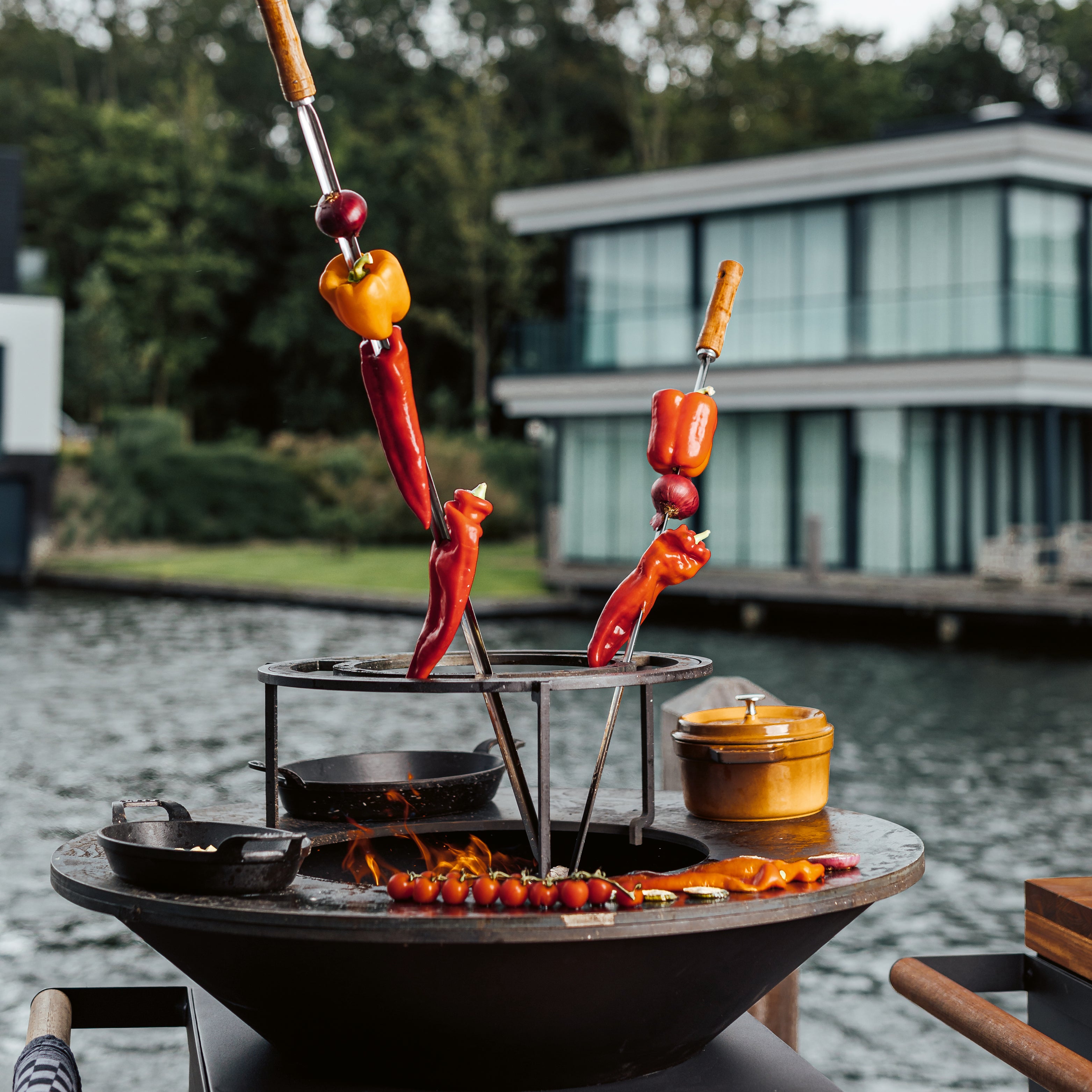 Accessoires zum Kochen im Garten, inszeniert rund um eine moderne Feuer- und Grillstation