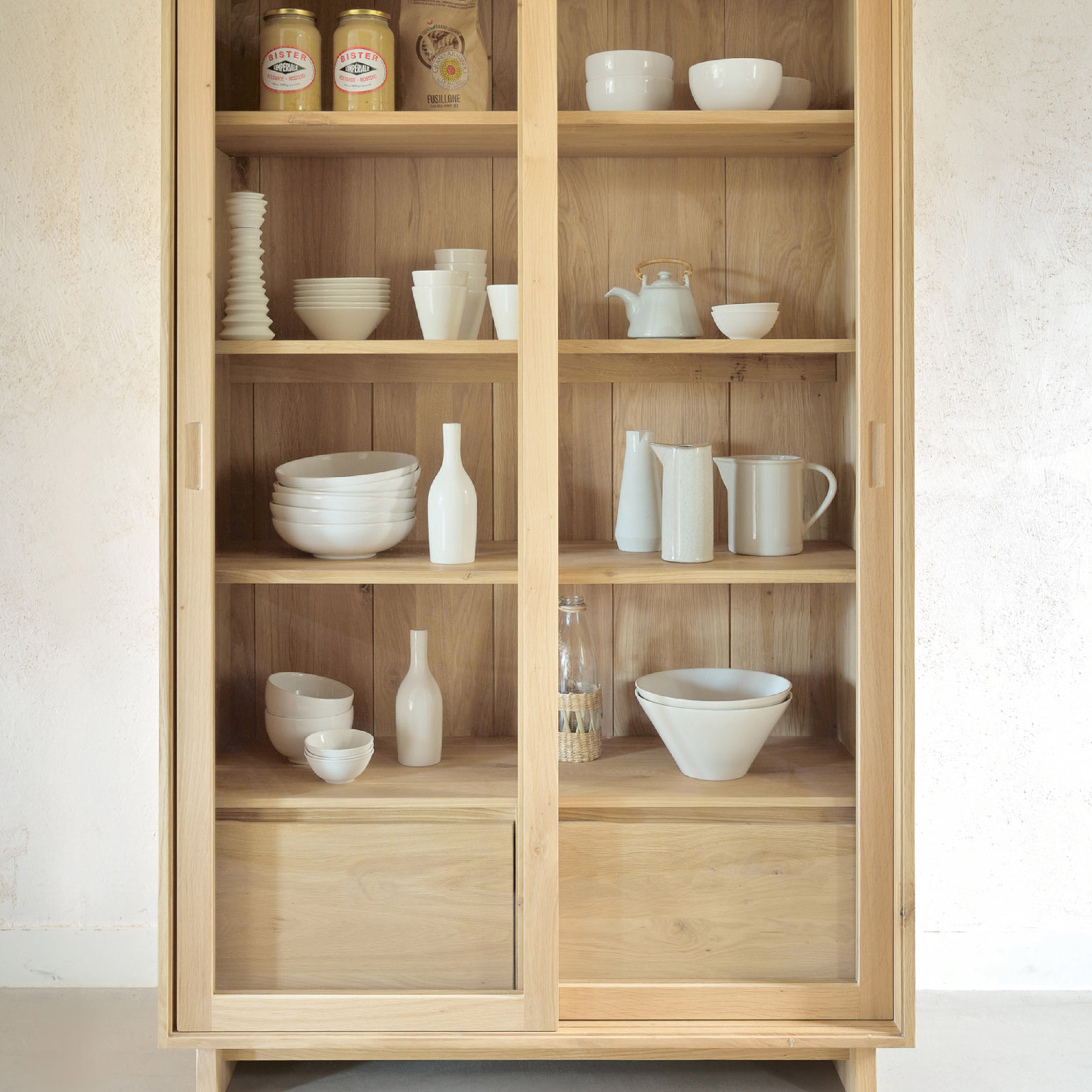 Geschirrschrank aus Massivholz im Design mit Glasfront und offen präsentierten Keramikobjekten