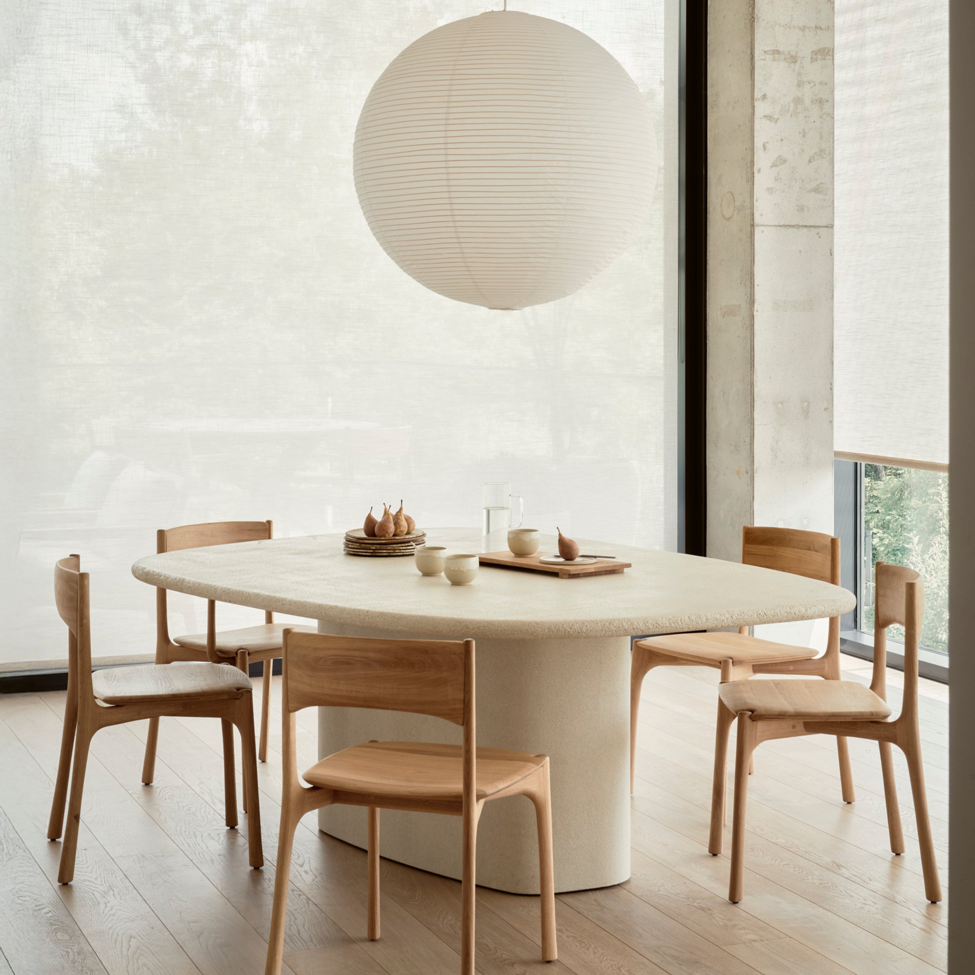 Ovaler Esstisch aus Mikrozement aus der Elements Kollektion von Ethnicraft, kombiniert mit fünf minimalistischen PI-Stühlen aus massiver Eiche – stilvoller Essbereich in natürlicher Ästhetik