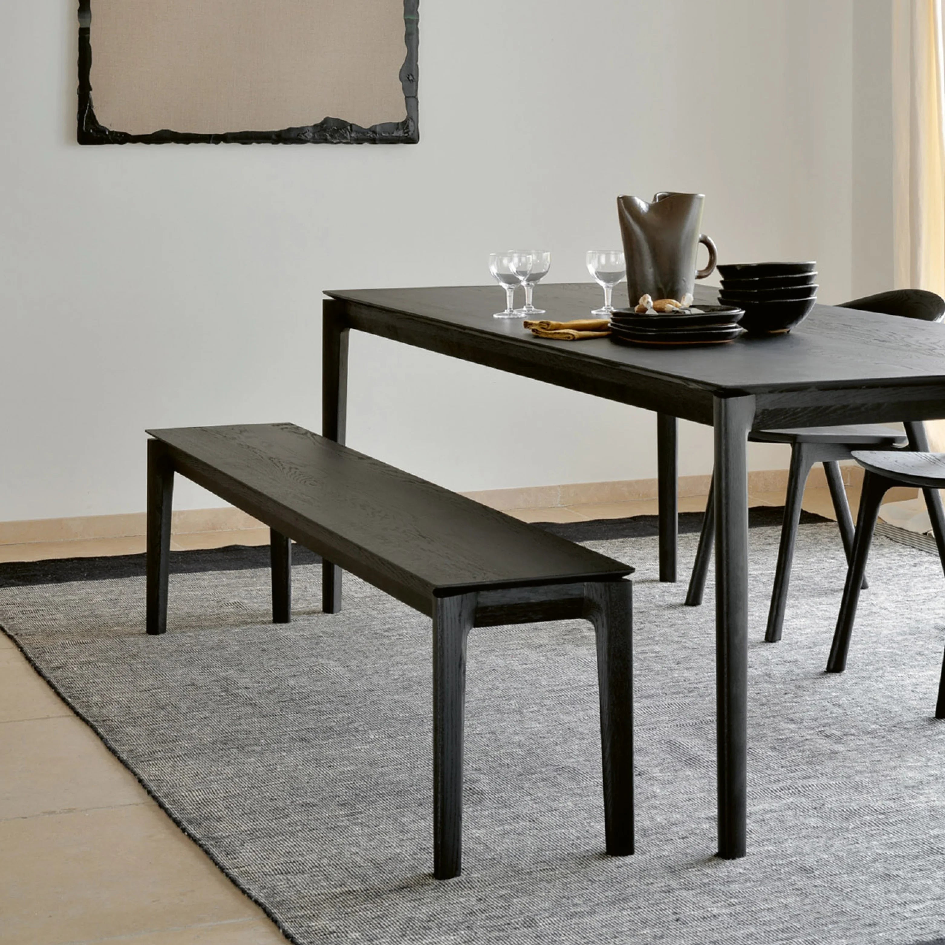 Moderne Sitzbank aus dunklem Holz am Esstisch mit Stühlen auf grauem Teppich
