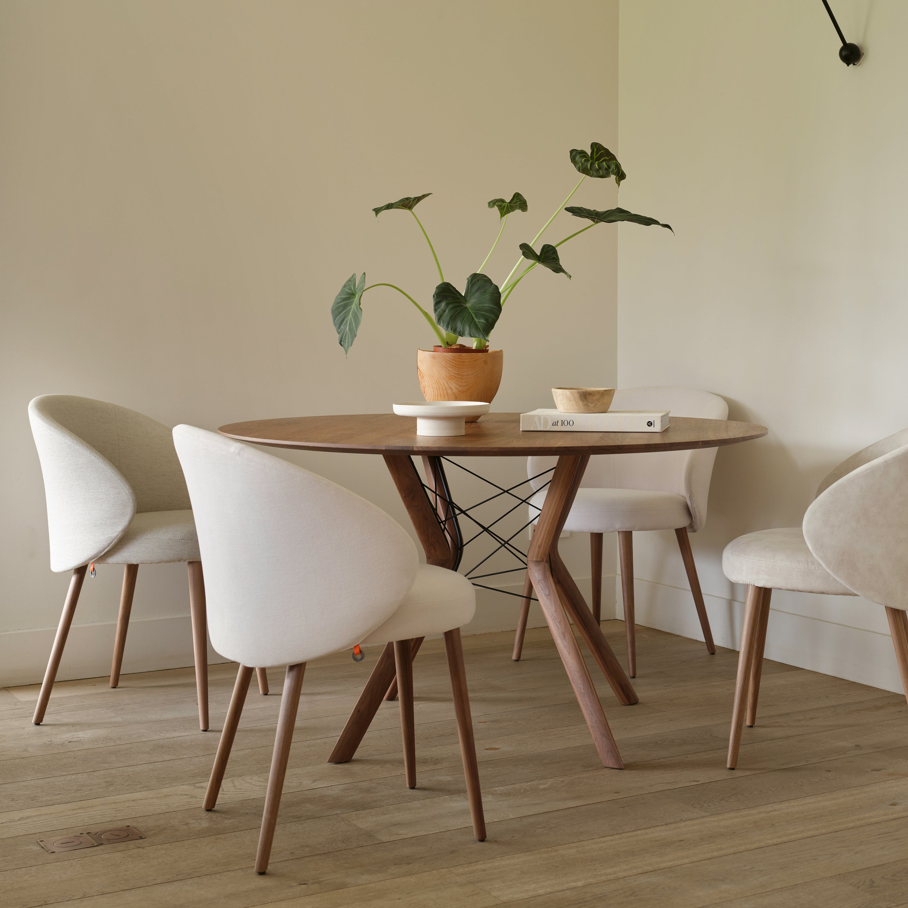 Runder Esstisch mit Massivholzgestell und vier gepolsterten Esszimmerstühlen mit Stoffbezug in Naturtönen – gemütlicher Essbereich mit Pflanze als Dekoration