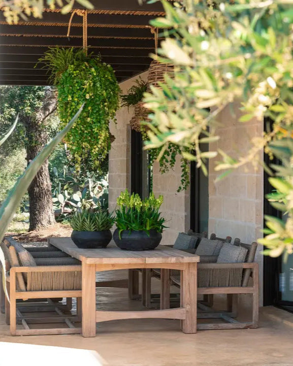 Jacoba Gartentisch im Low-Dining-Format – ausdrucksstarkes Teakholz in ruhiger Gartenszene mit mediterraner Atmosphäre