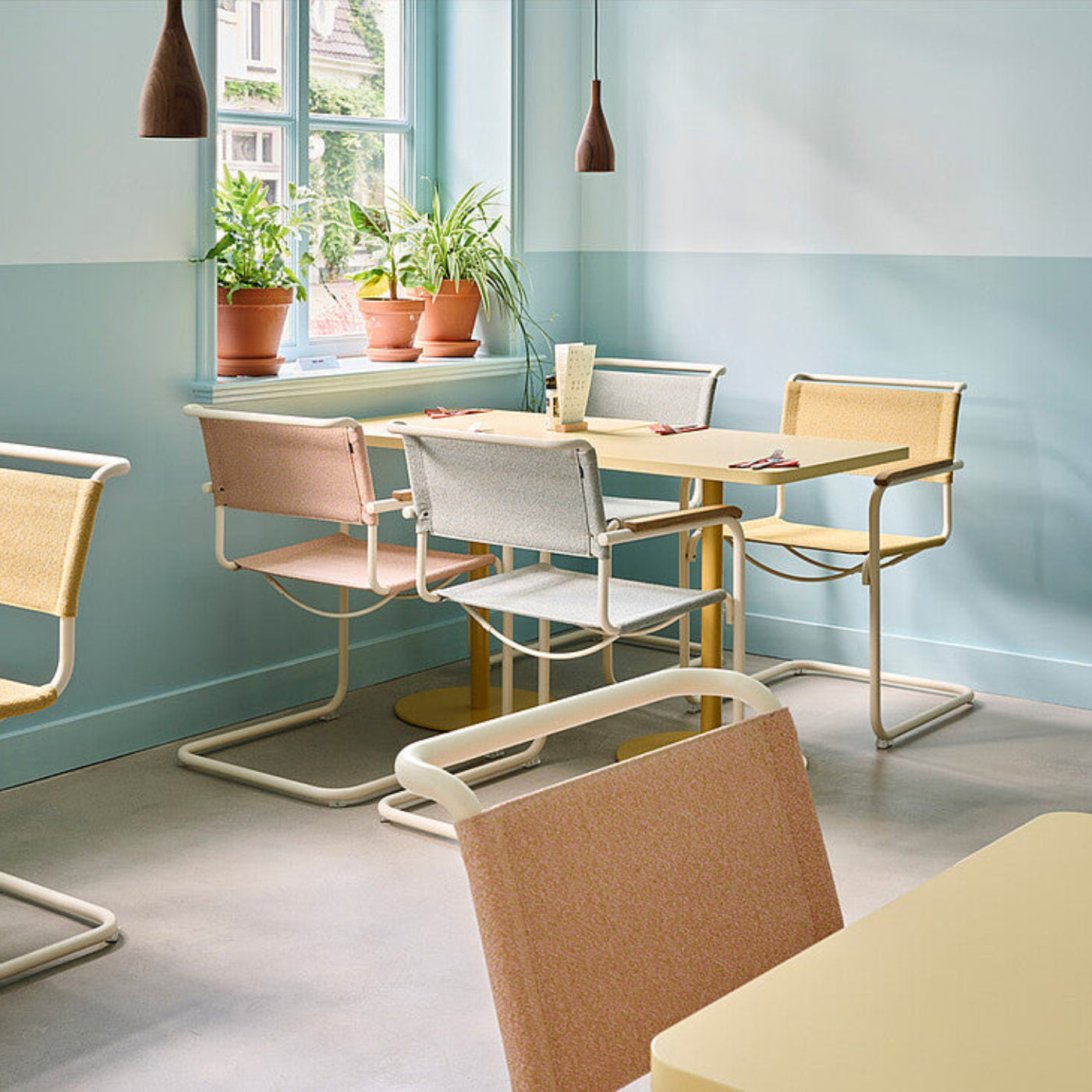 Thonet Freischwinger in verschiedenen Pastelltönen an Esstischen in einem hellen Restaurant