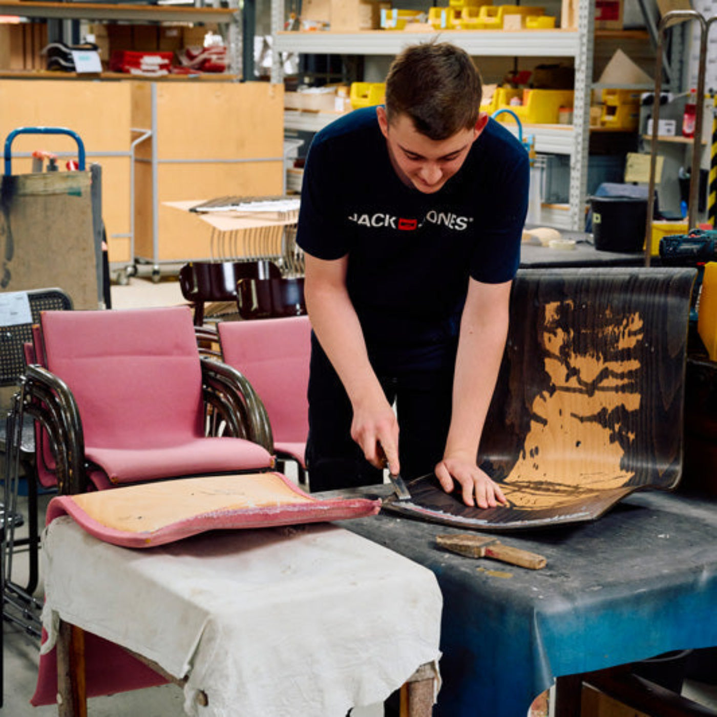 Mitarbeiter restauriert einen Thonet Stuhl von Hand in der Werkstatt.