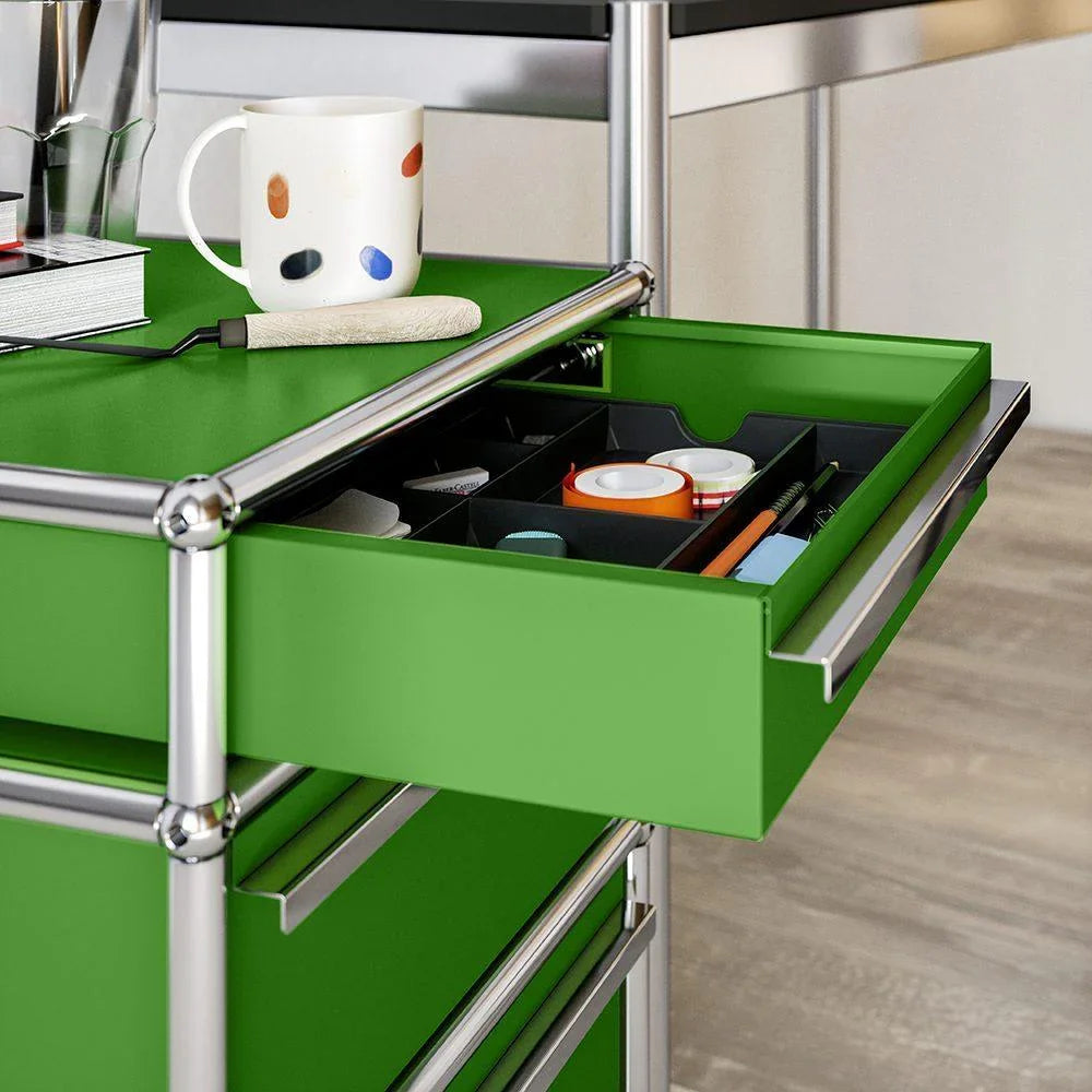 Offener Rollcontainer M63 von USM Haller in grün – praktische Einblickansicht mit offener Schublade, ideal für organisierte Dokumentenablage im Designbüro oder Homeoffice