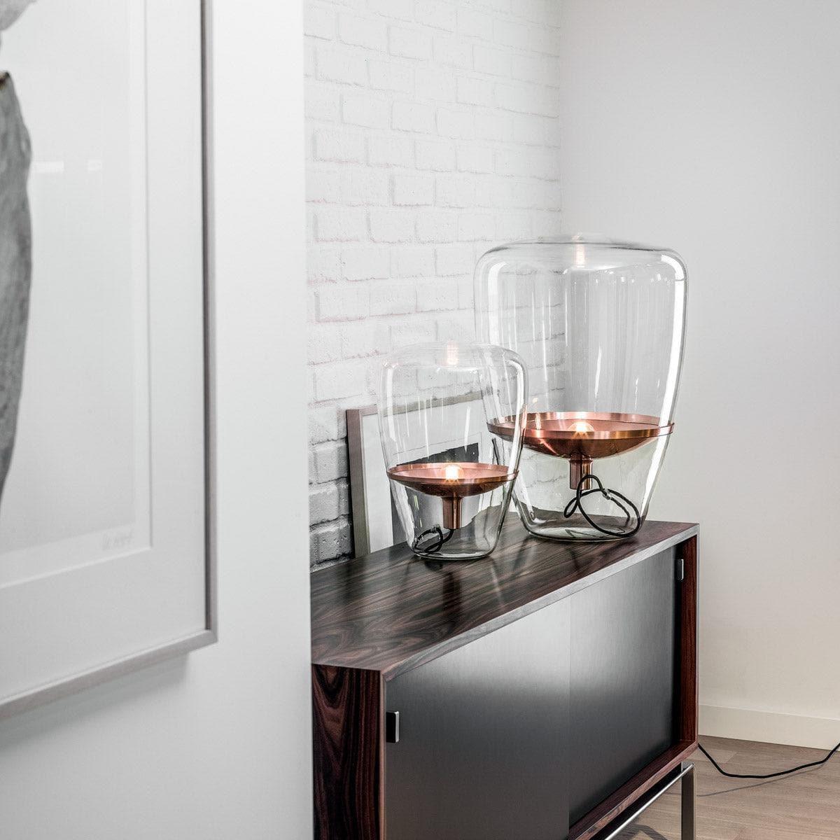 Brokis BALLOONS PC857 Tischleuchte mit klarem Glas und Kupferreflektor auf einem Holztisch – moderne Lichtakzentuierung im Interieur