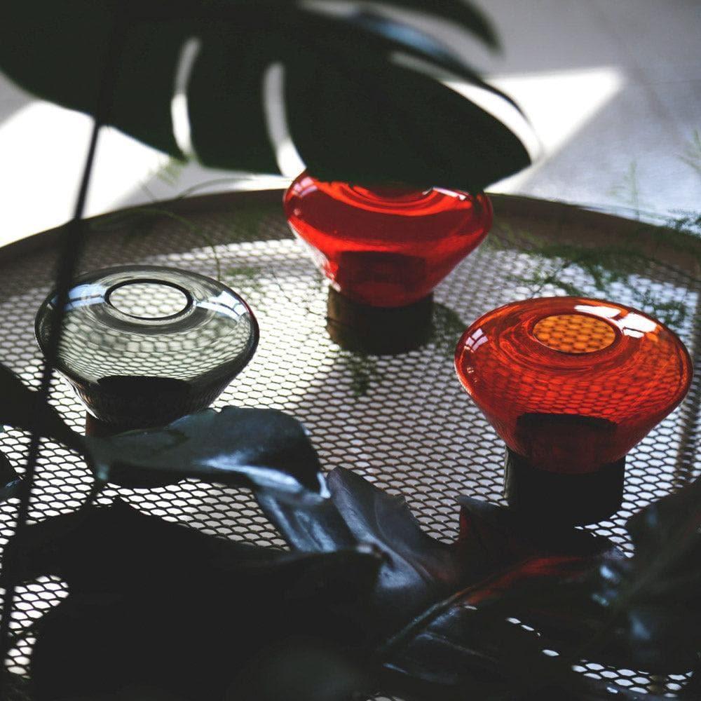 Drei unterschiedliche MUFFIN Windlichter von Brokis auf einem Tisch arrangiert – Designleuchten in variierenden Farben und Größen für stimmungsvolle Atmosphäre