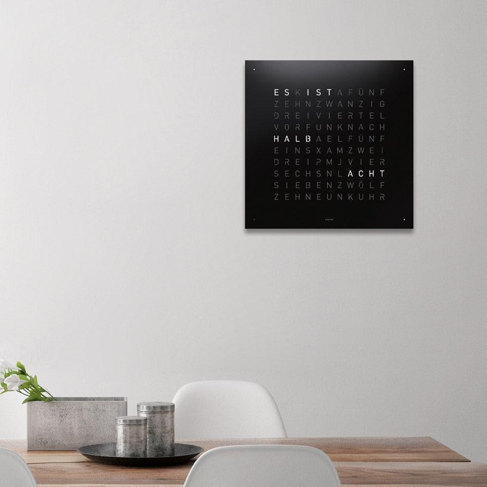 QLOCKTWO EARTH 45 Black Pepper – schwarze Designer-Wanduhr in strukturierter Stahloptik, harmonisch integriert in ein modernes Interieur